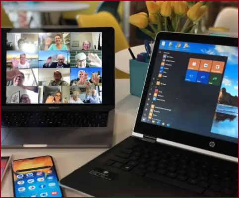 Monitor mit Konferenzteilnehmern neben anderen Notebook symbolisiert Videokonferenzen