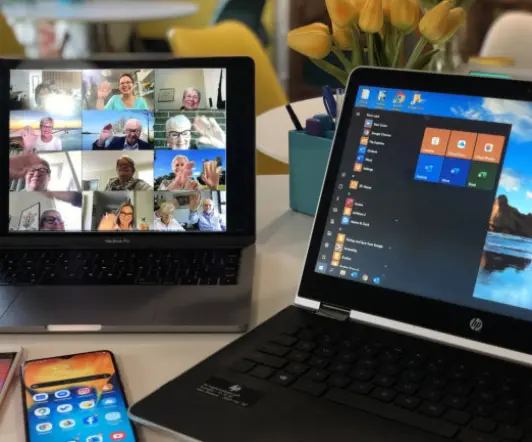 Monitor mit Konferenzteilnehmern neben anderen Notebook symbolisiert Videokonferenzen